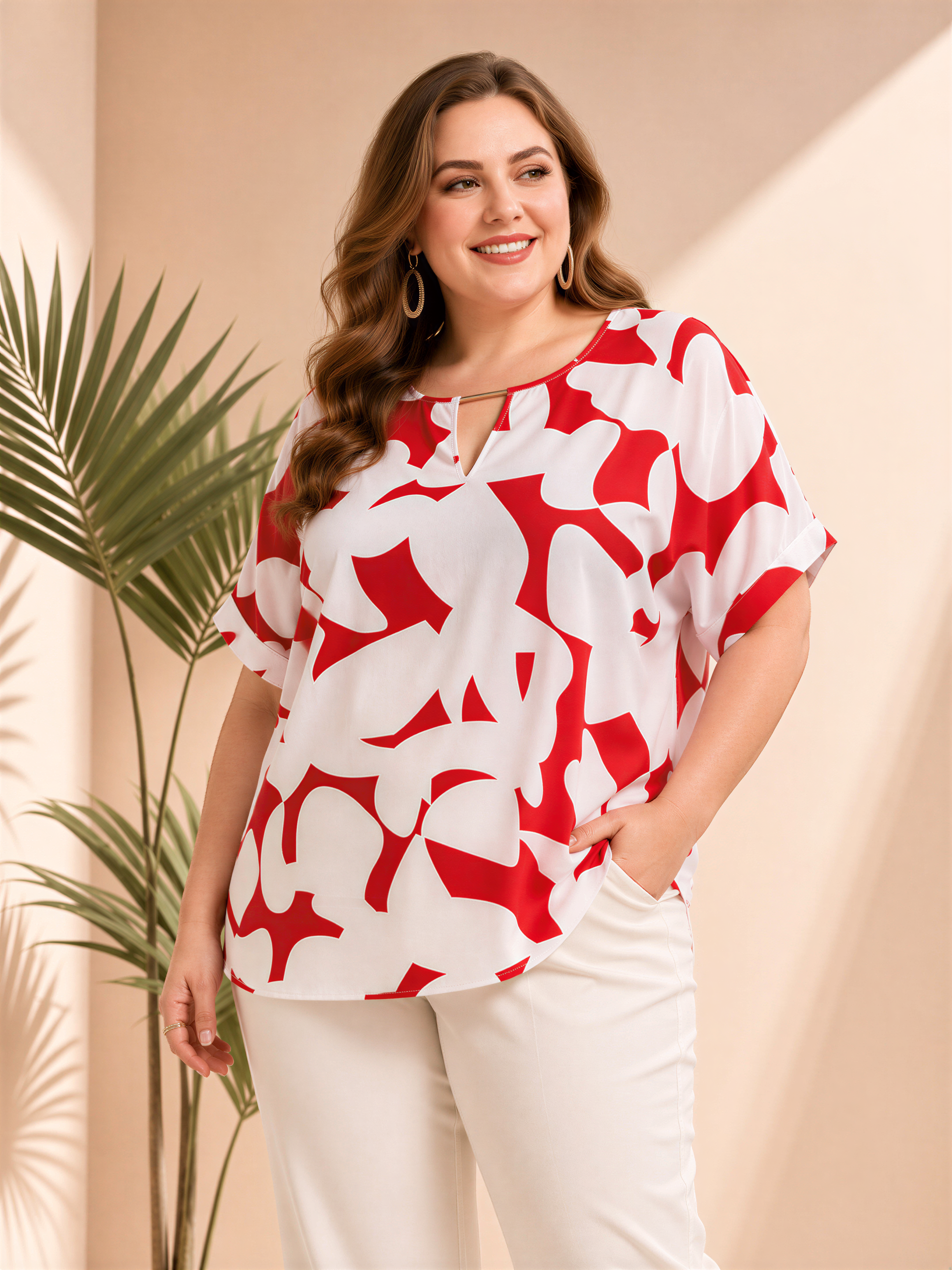 A woman wearing a red and white patterned blouse stands in front of a palm plant, smiling at the camera.