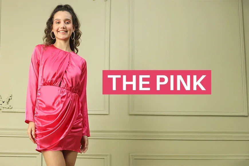 Woman in a satin pink mini dress with long sleeves, smiling against a light wall