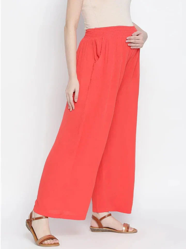 Woman wearing coral wide leg high waist palazzo pants with pockets and sandals