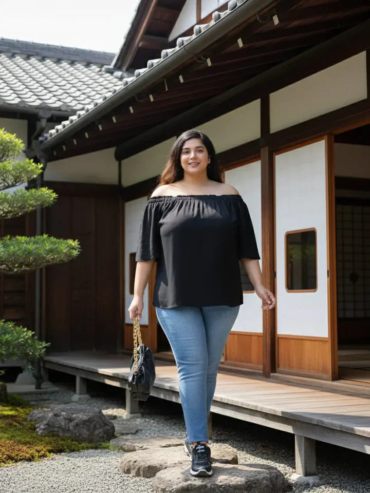 Plus size woman in black short-sleeve shift dress with side slit, posing against white background