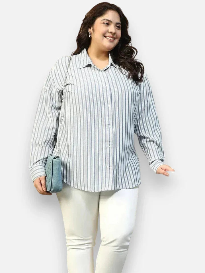 Plus size woman in striped button-down shirt and white pants, carrying a blue shoulder bag