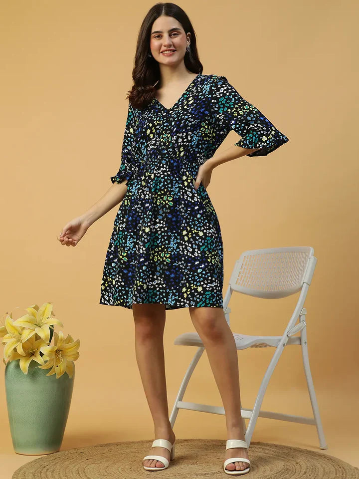 Woman in floral print V-neck dress with 3/4 sleeves, plus size fashion, styled with white sandals and vase of yellow flowers