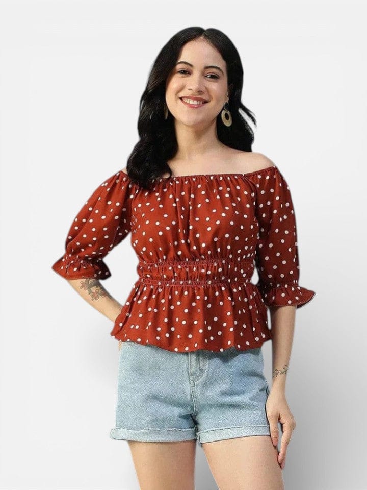 Woman wearing a red polka dot off-shoulder top with puff sleeves and light denim shorts