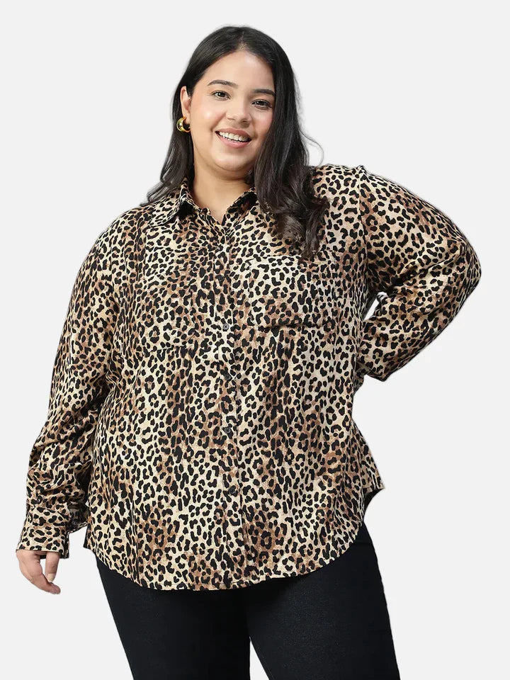 Plus size woman in a long sleeve leopard print shirt and black pants, smiling