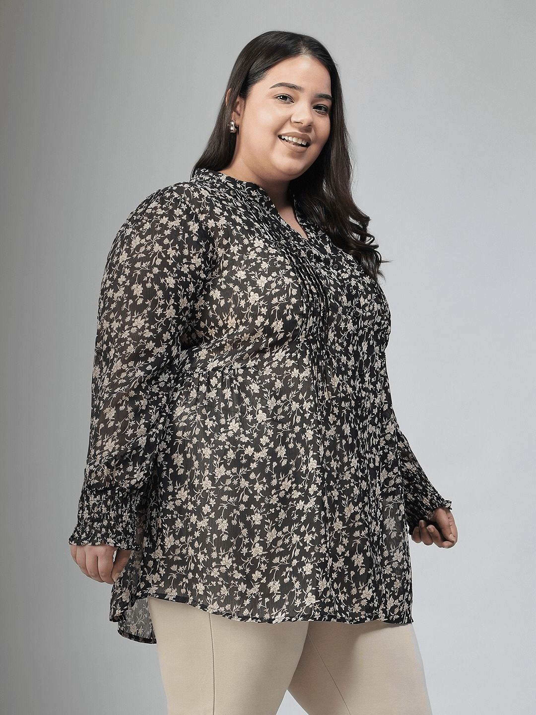 Woman wearing a black floral blouse against a gray background