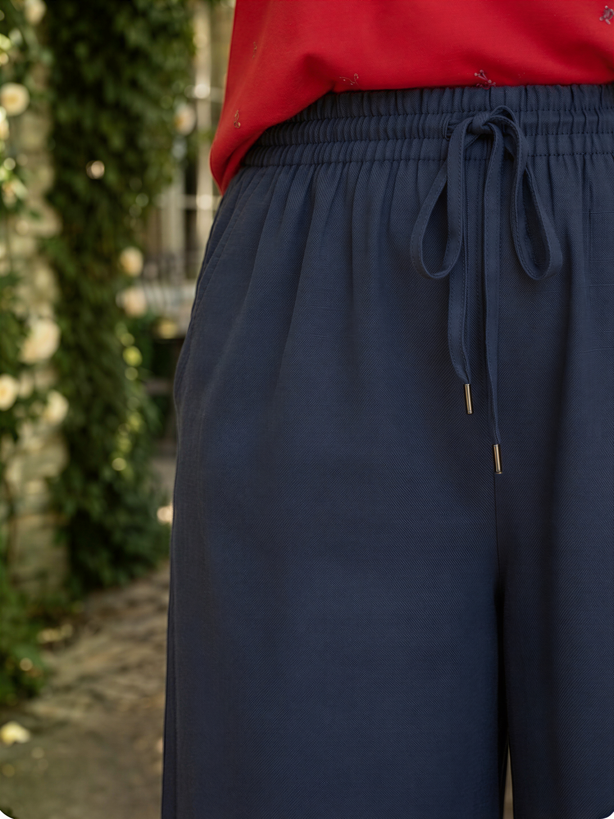 A close-up view of a person wearing navy blue pants with a red top.