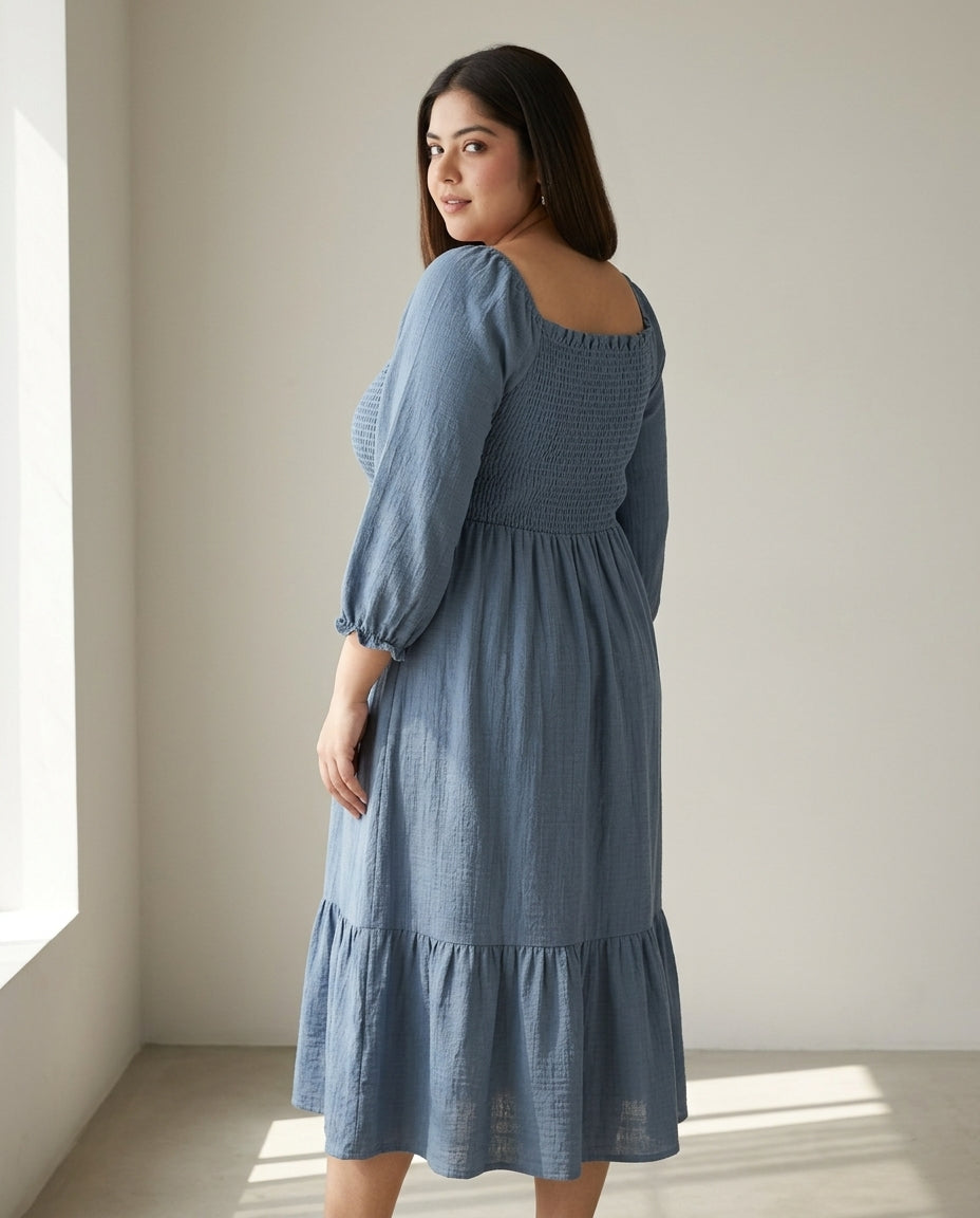 Plus size woman in a blue, long sleeve, midi casual dress with smocked bodice
