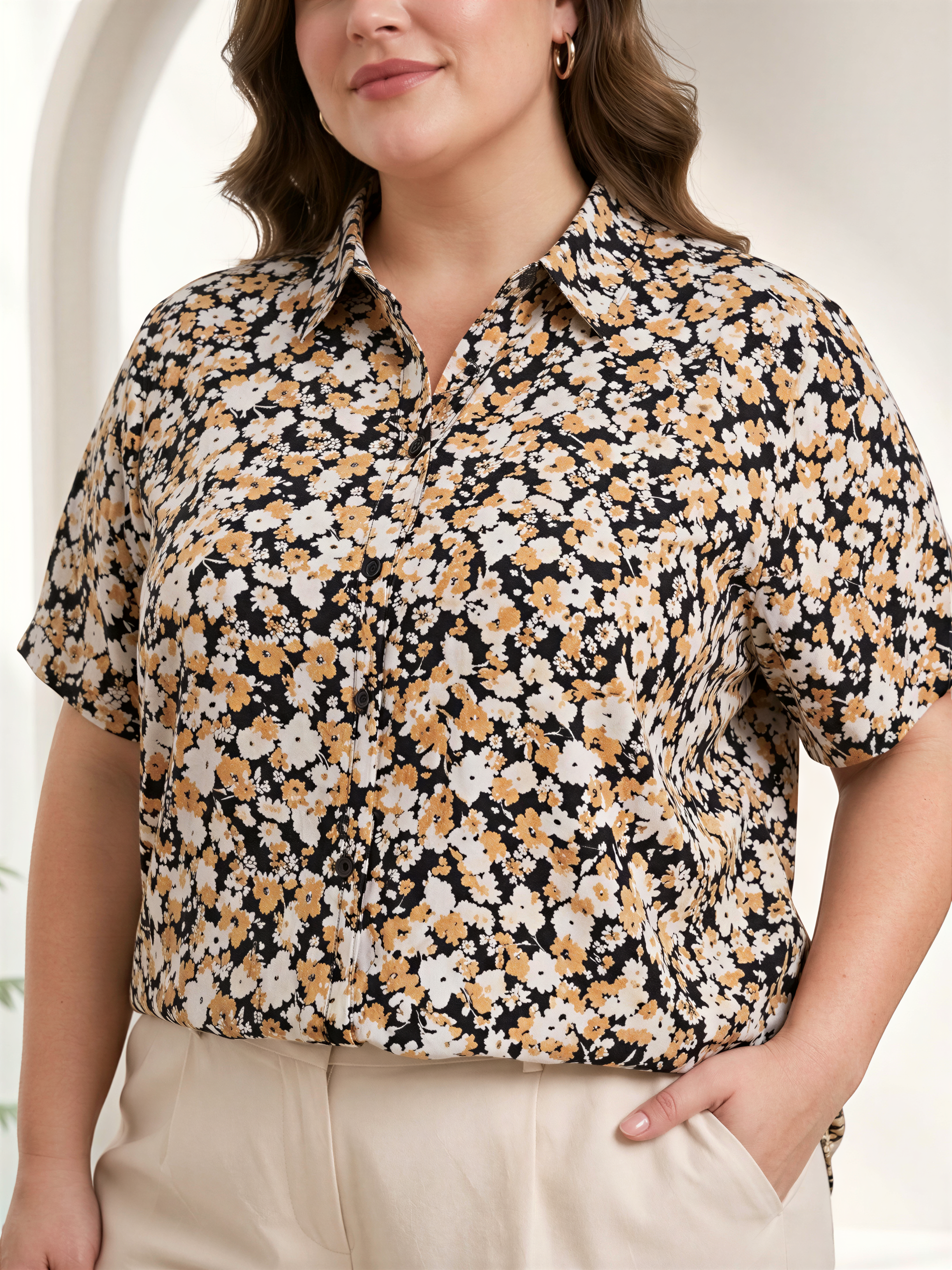 A woman wearing a floral print shirt and beige pants, smiling at the camera.