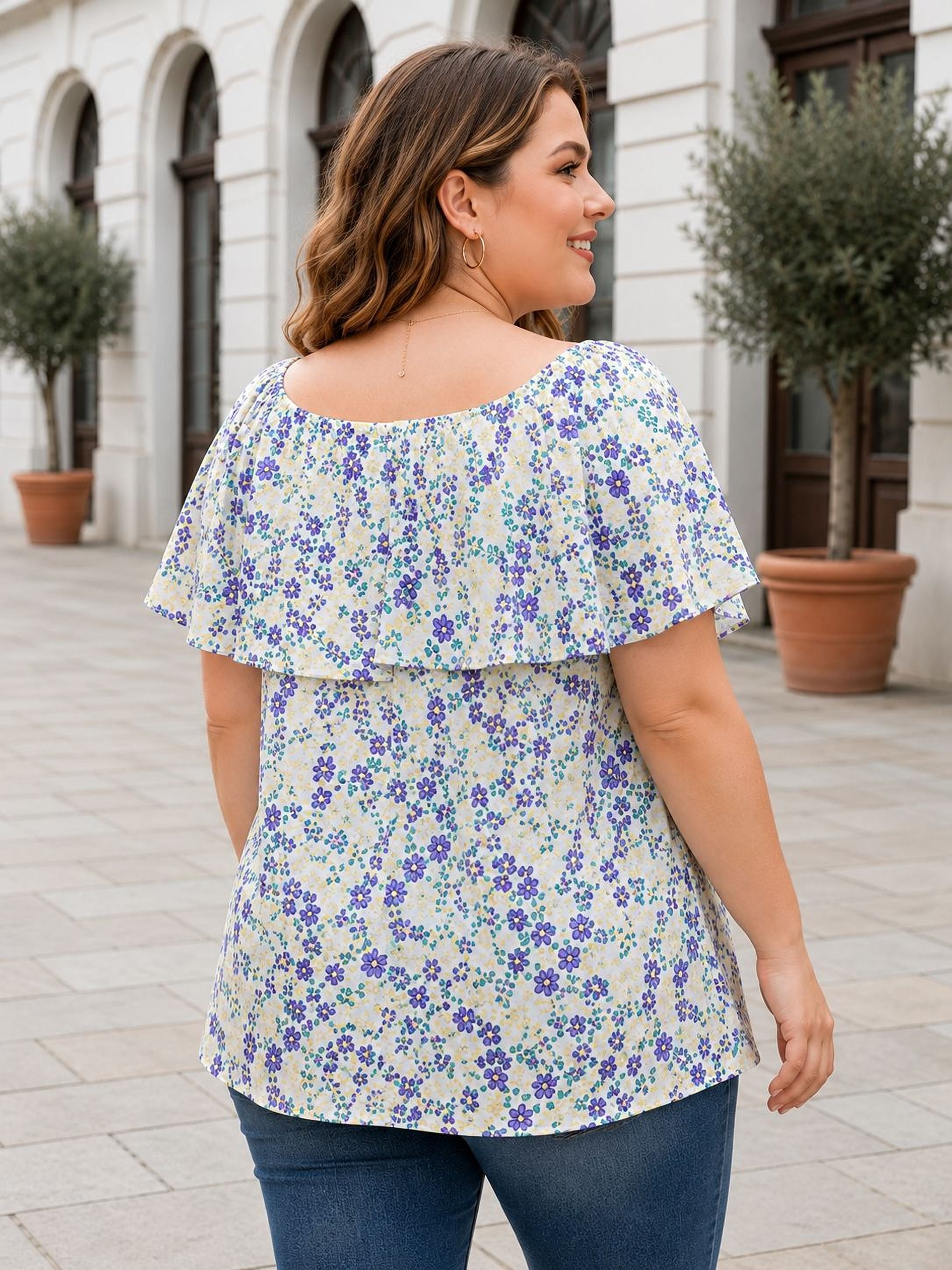 A woman wearing a floral print blouse is standing in front of a building with arched windows.