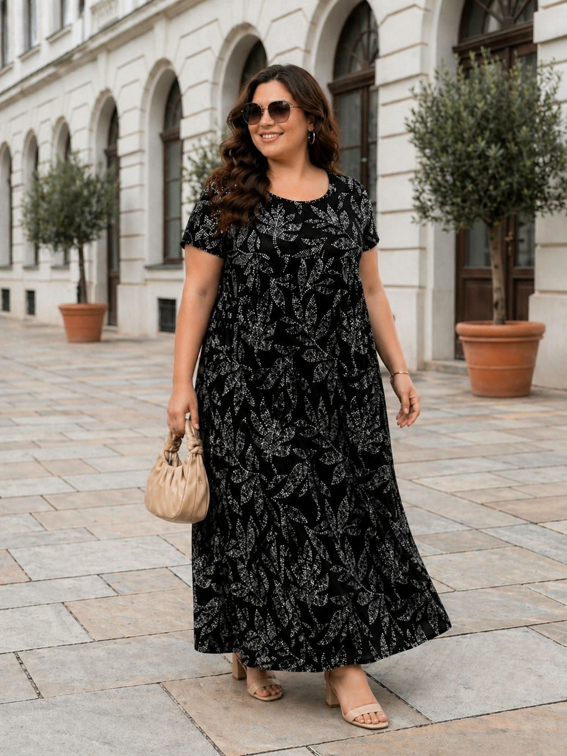 A woman wearing a black and white floral dress, sunglasses, and carrying a small purse is walking on a sidewalk in front of a building with arched windows.