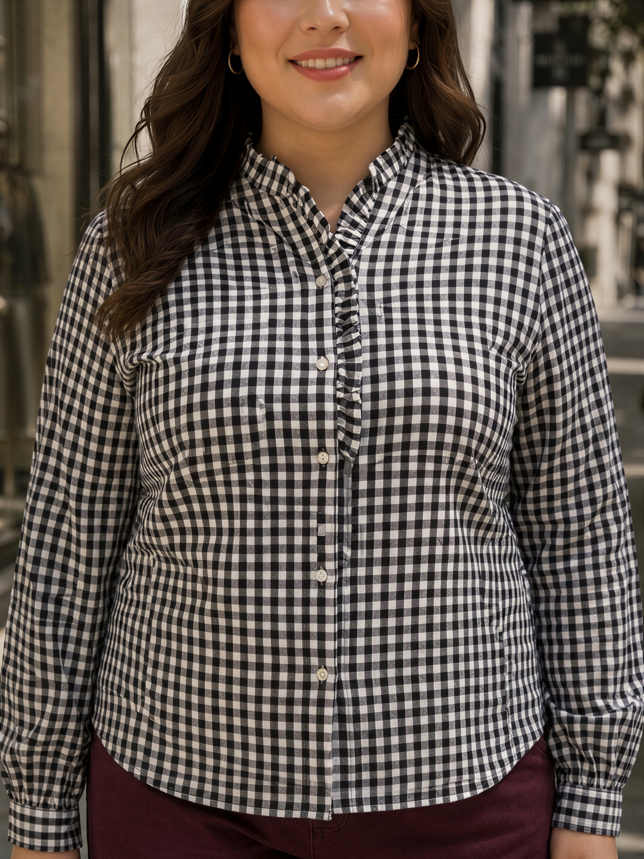 A woman wearing a black and white checkered shirt with a collar and buttons, smiling at the camera.