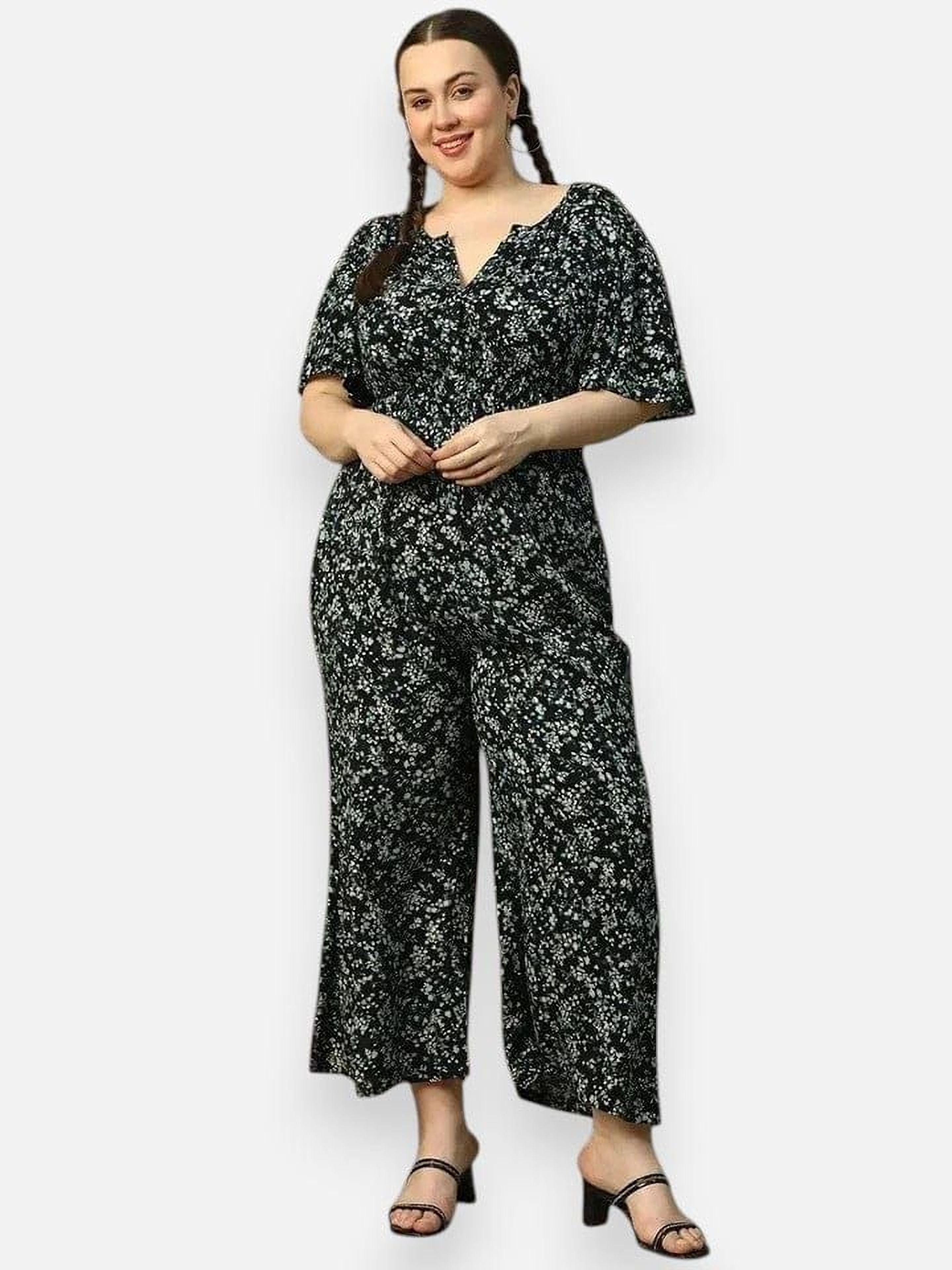 A woman wearing a black and white floral jumpsuit with a high neckline and short sleeves, posing for a photograph.