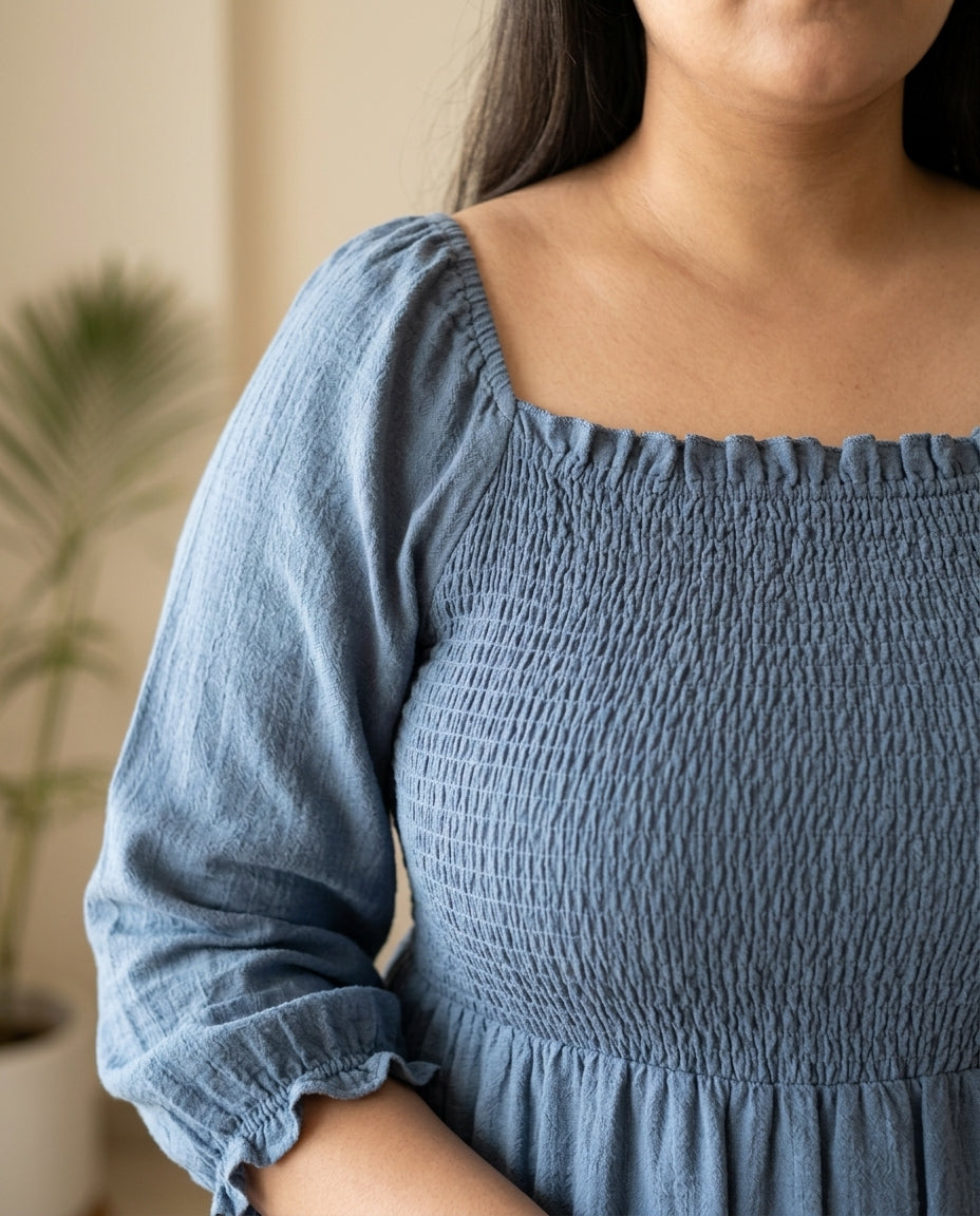 Plus size woman wearing blue smocked long sleeve dress with square neckline