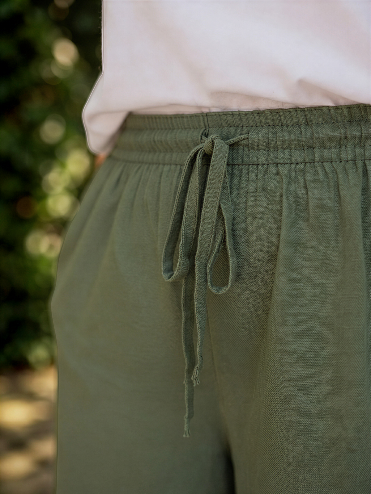 A close-up view of a person wearing olive green cargo pants with a drawstring waist.