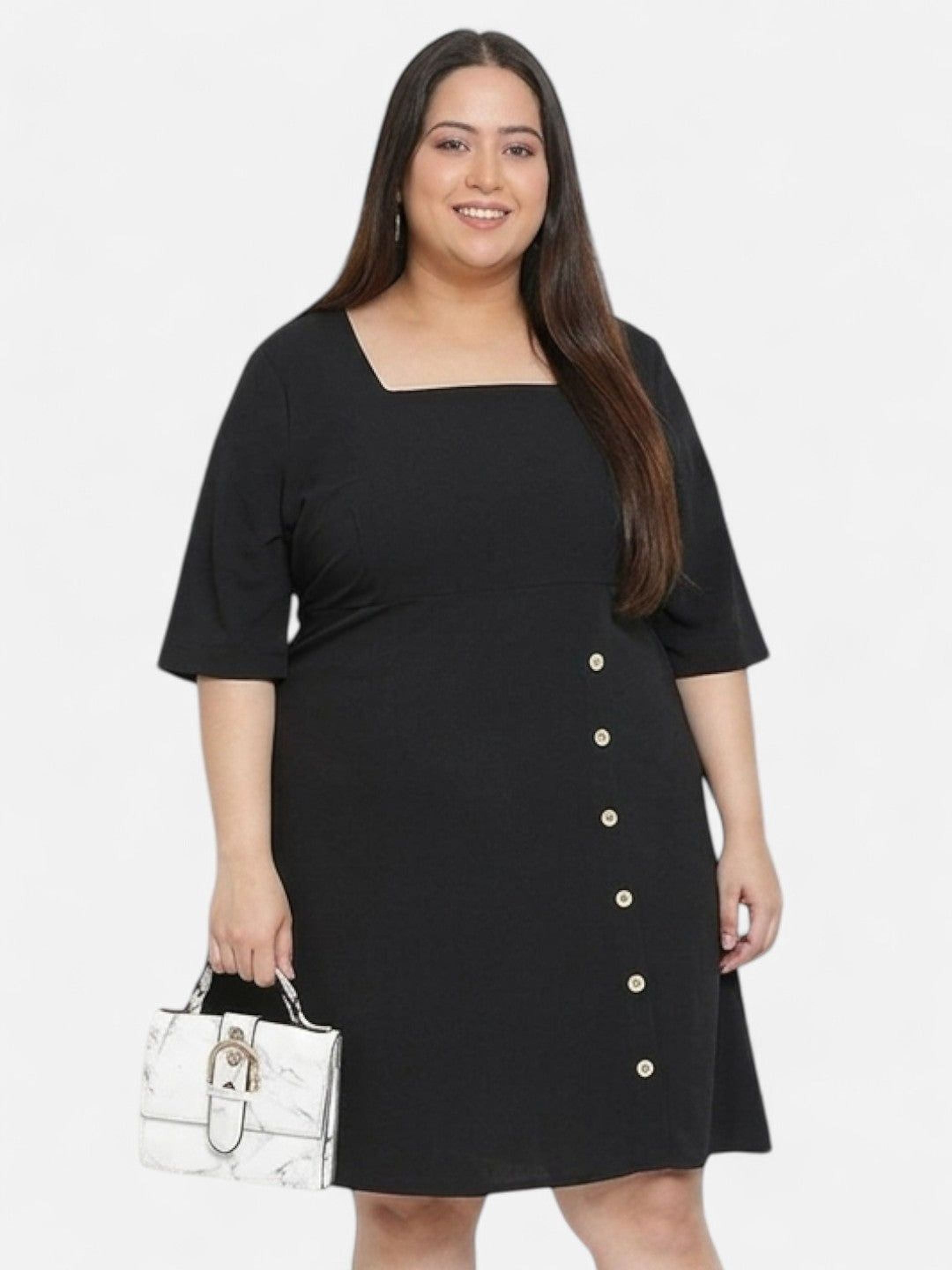 A woman wearing a black dress with buttons and smiling at the camera.