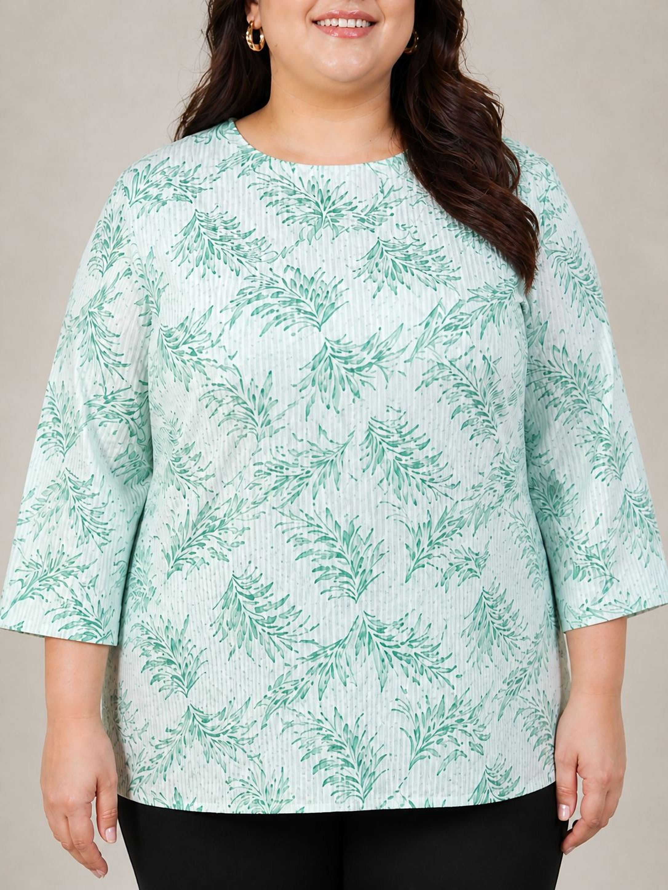 A woman wearing a light green blouse with a leaf pattern, smiling at the camera.