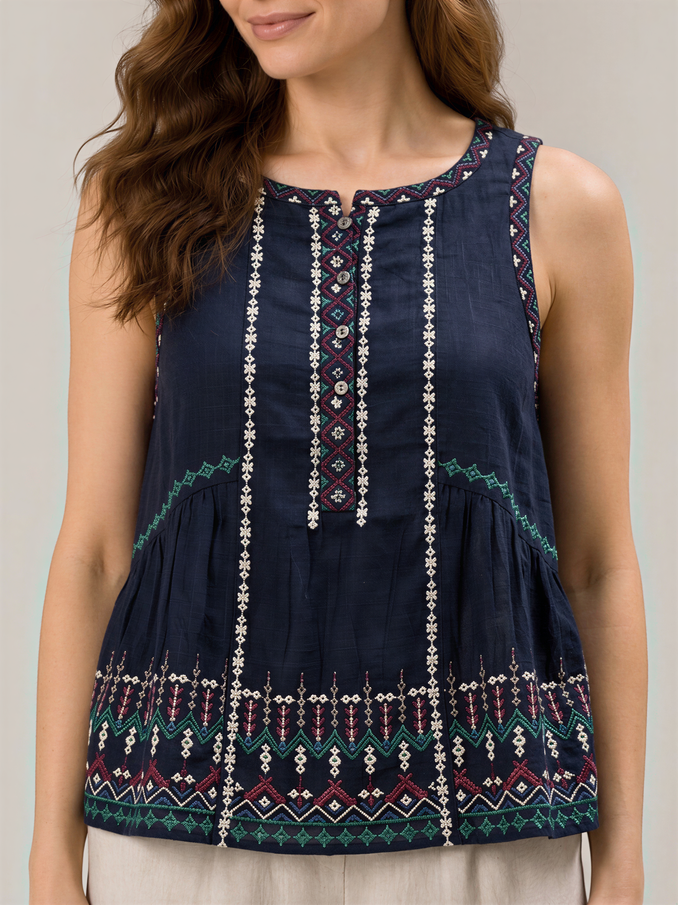 A woman wearing a navy blue sleeveless top with a patterned design and a v-neck.