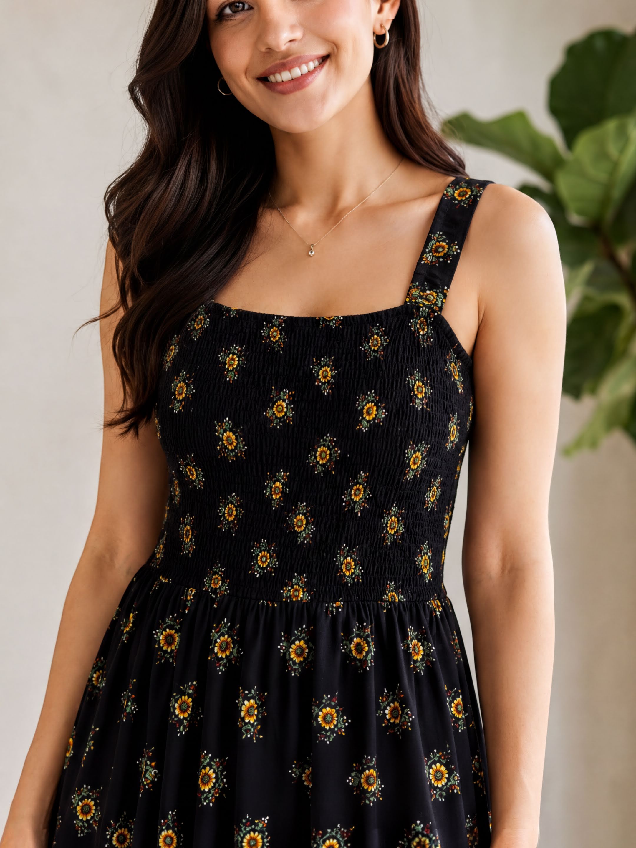 A woman wearing a black dress with yellow sunflower patterns, smiling at the camera.