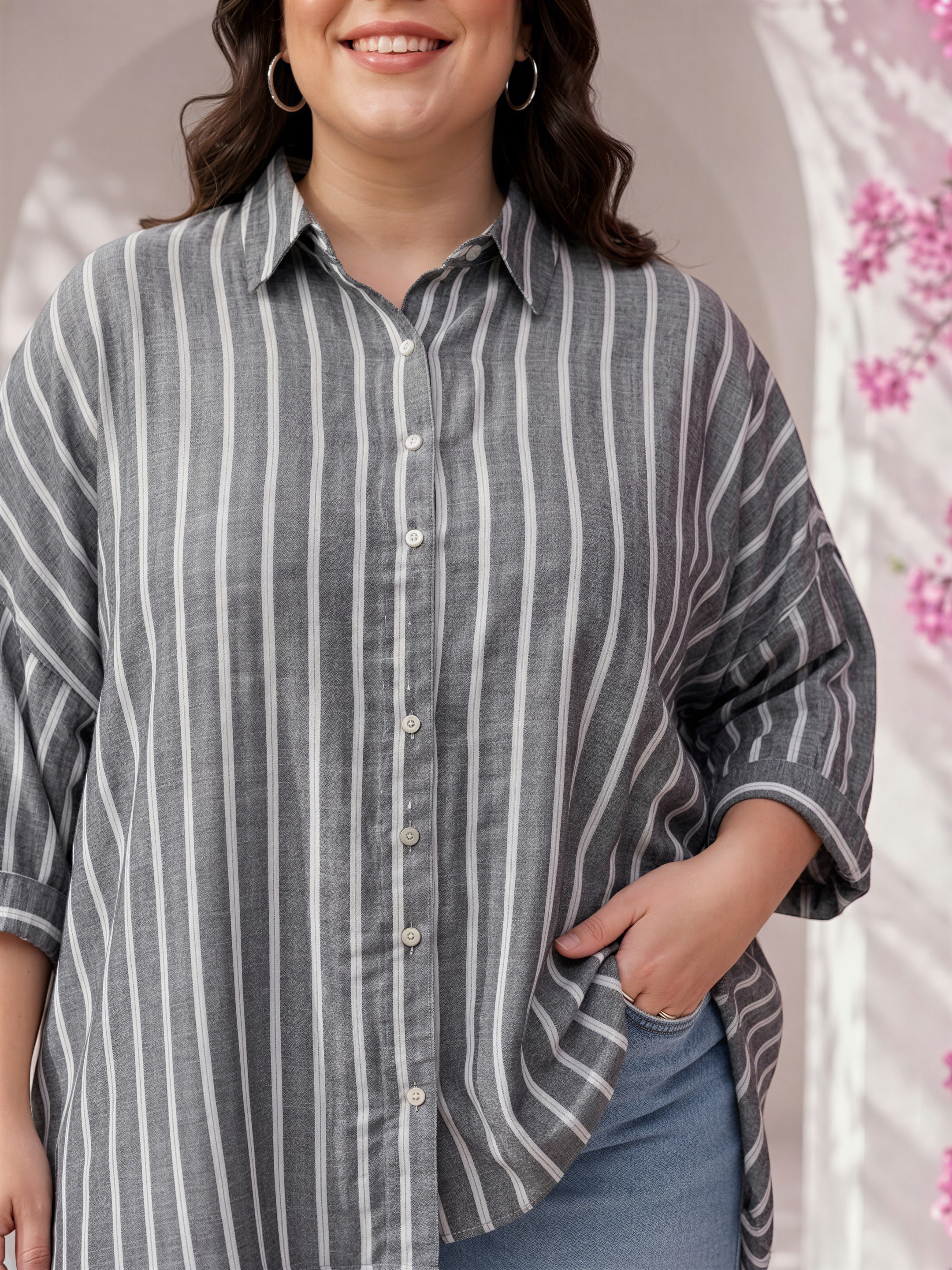 A woman wearing a gray and white striped shirt with a collar and buttons, smiling and looking at the camera.