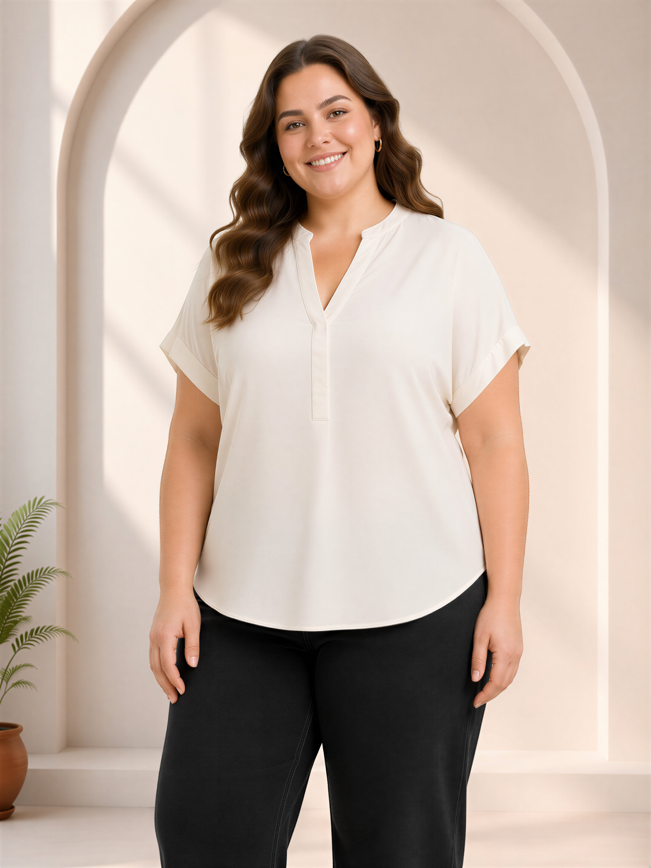 A woman with long brown hair is standing in front of a white archway, smiling at the camera.