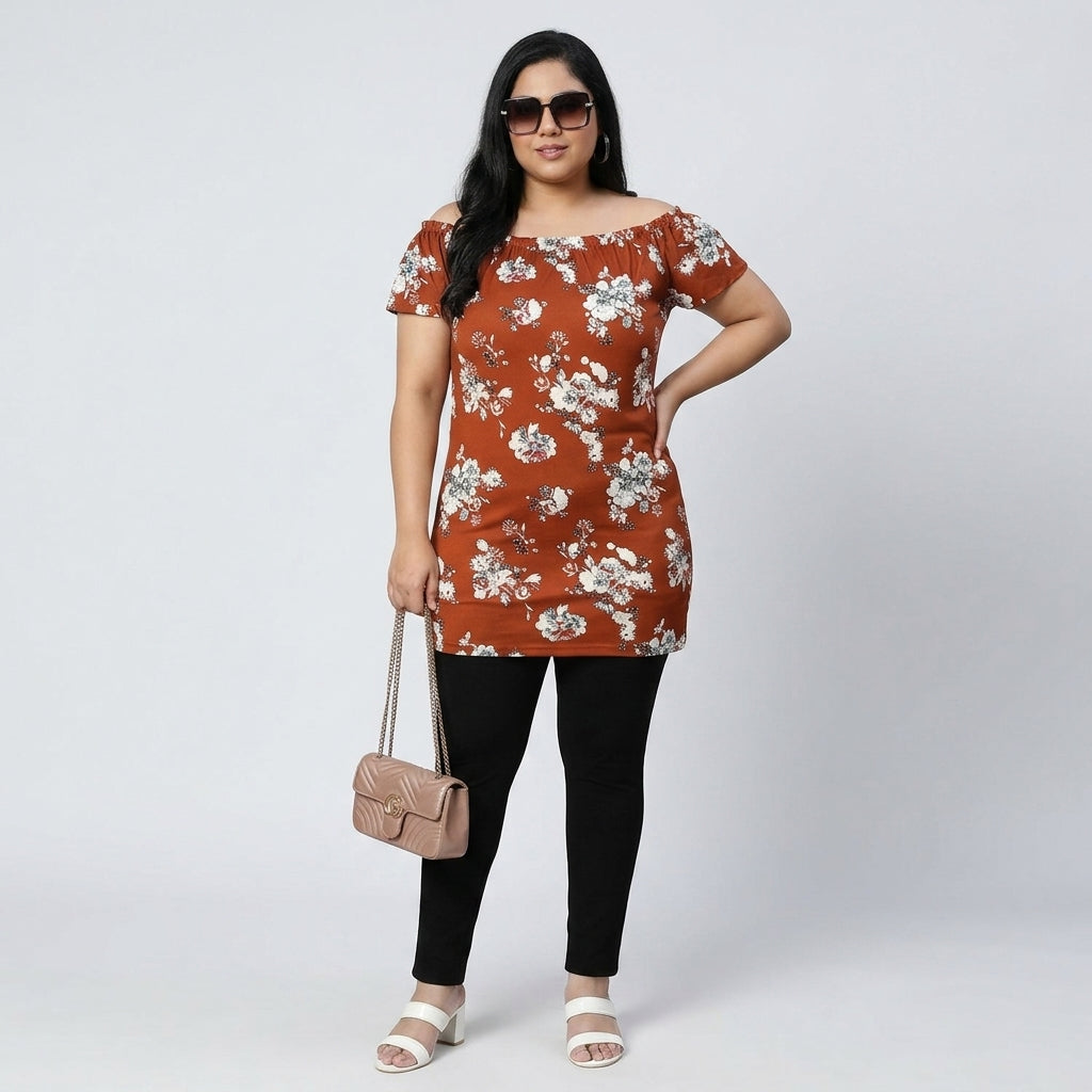 Plus size woman in brown floral off-shoulder tunic with black leggings, holding beige purse