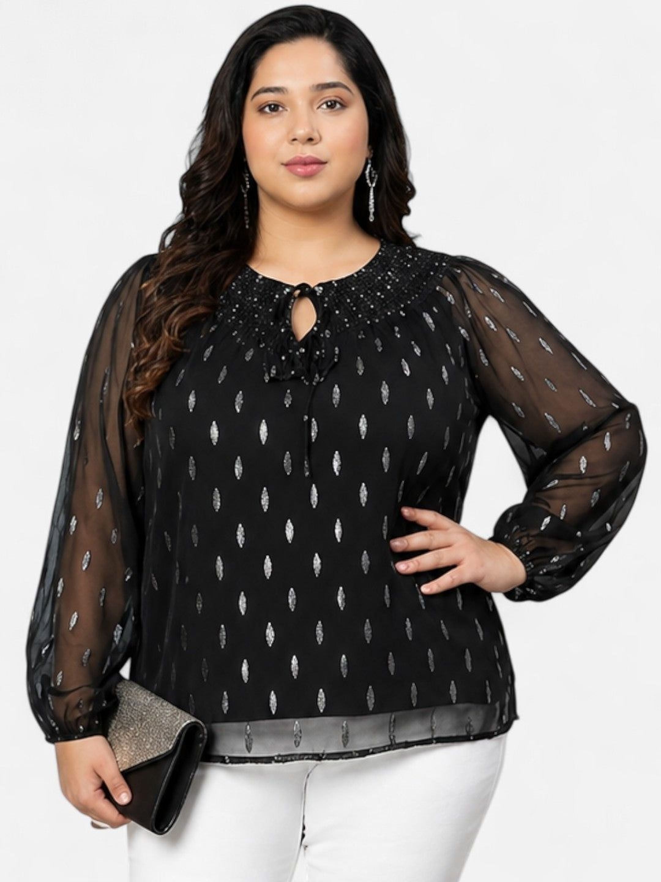 A woman with long dark hair wearing a black blouse with silver dots, posing for a photograph.