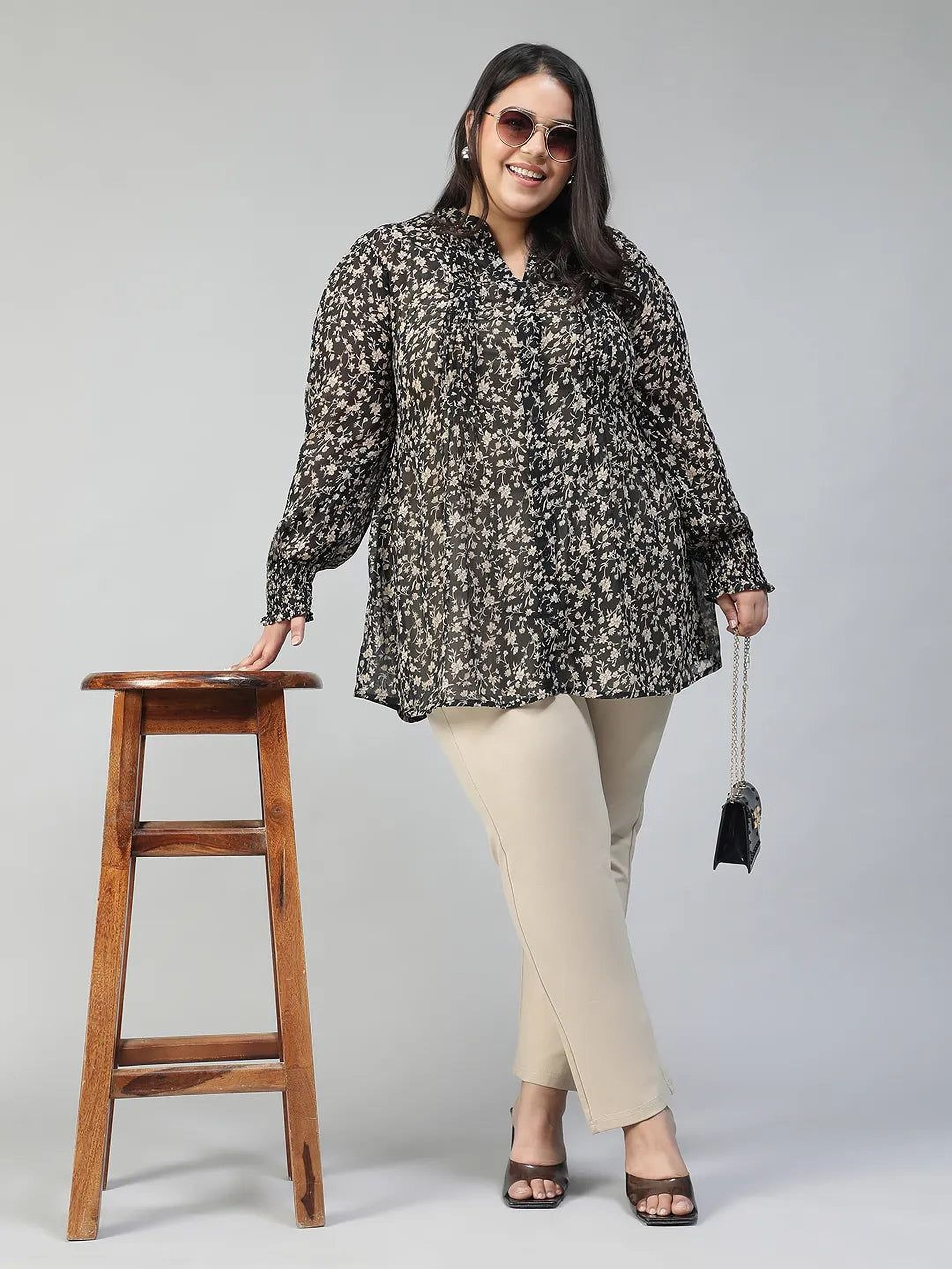Woman wearing a black floral blouse against a gray background