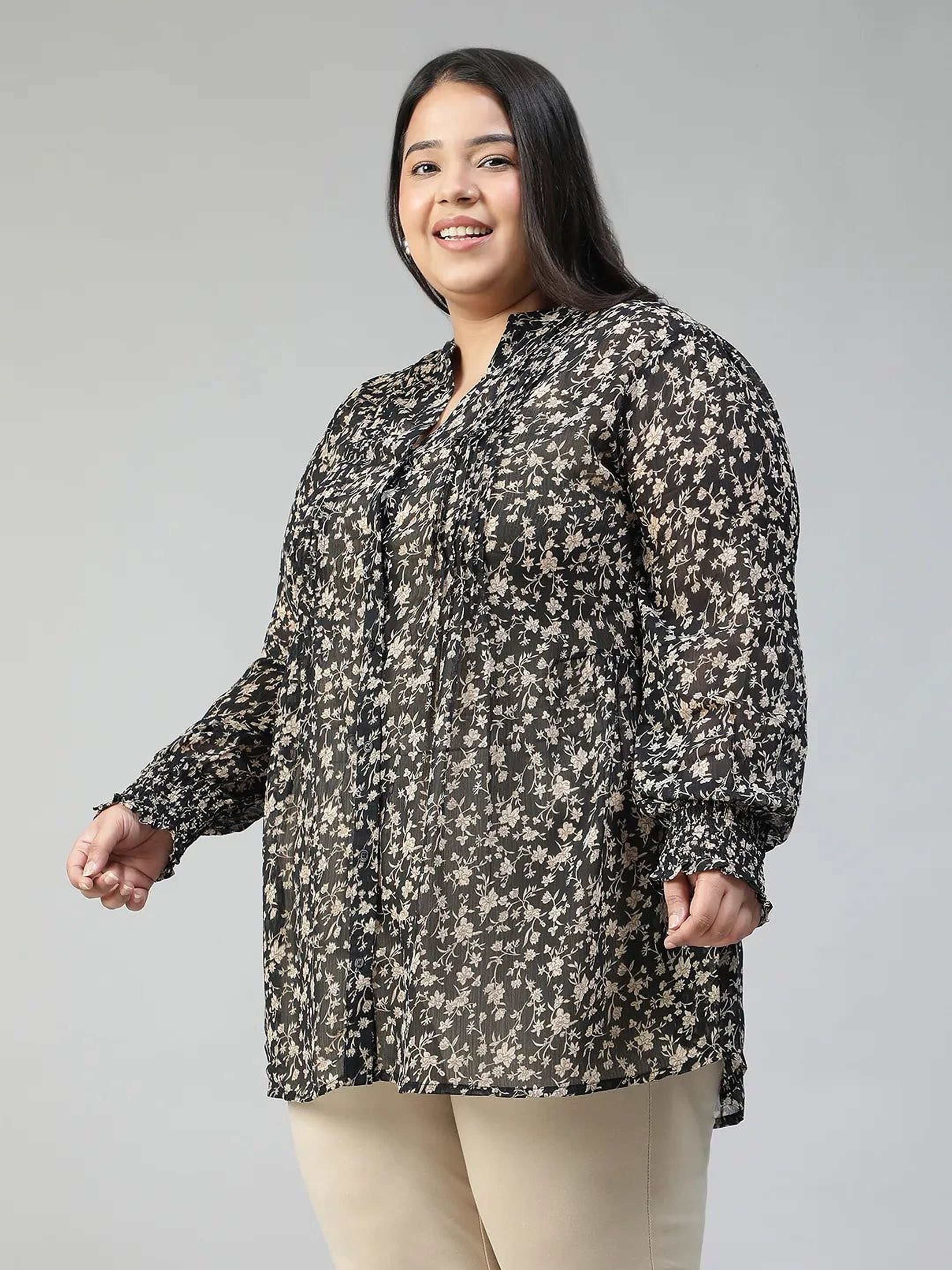 Woman wearing a black floral blouse against a gray background