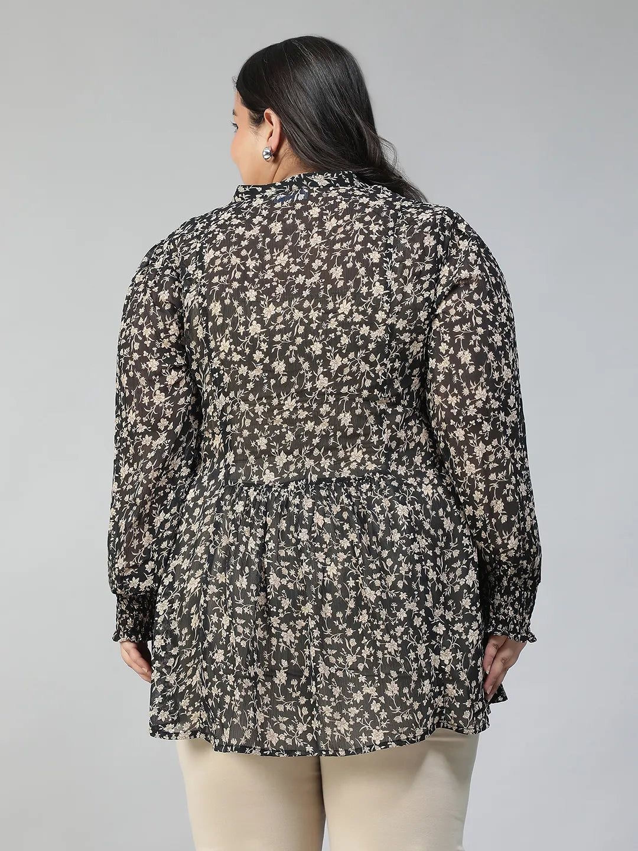 Woman wearing a black floral blouse against a gray background