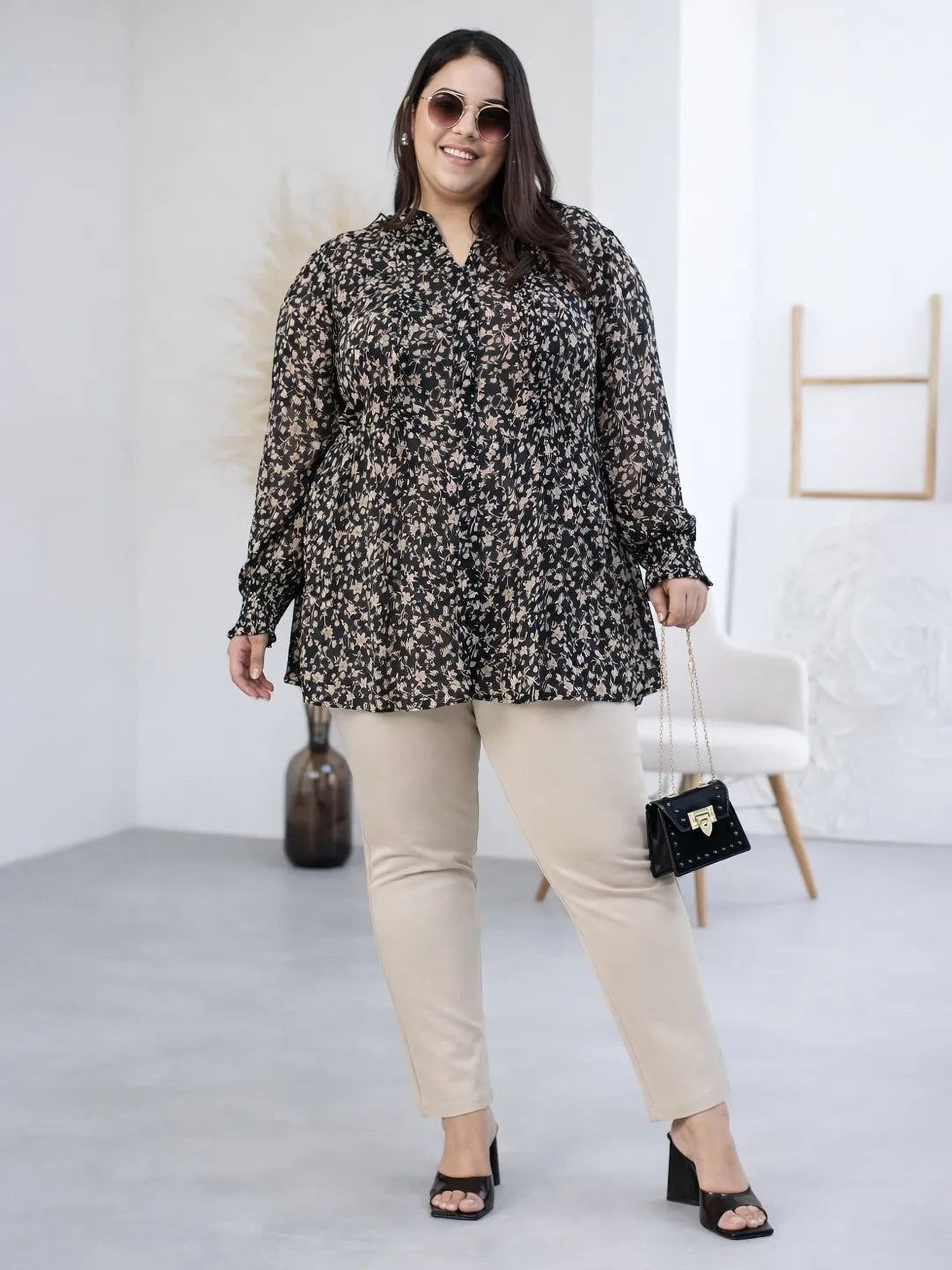 Woman wearing a black floral blouse against a gray background