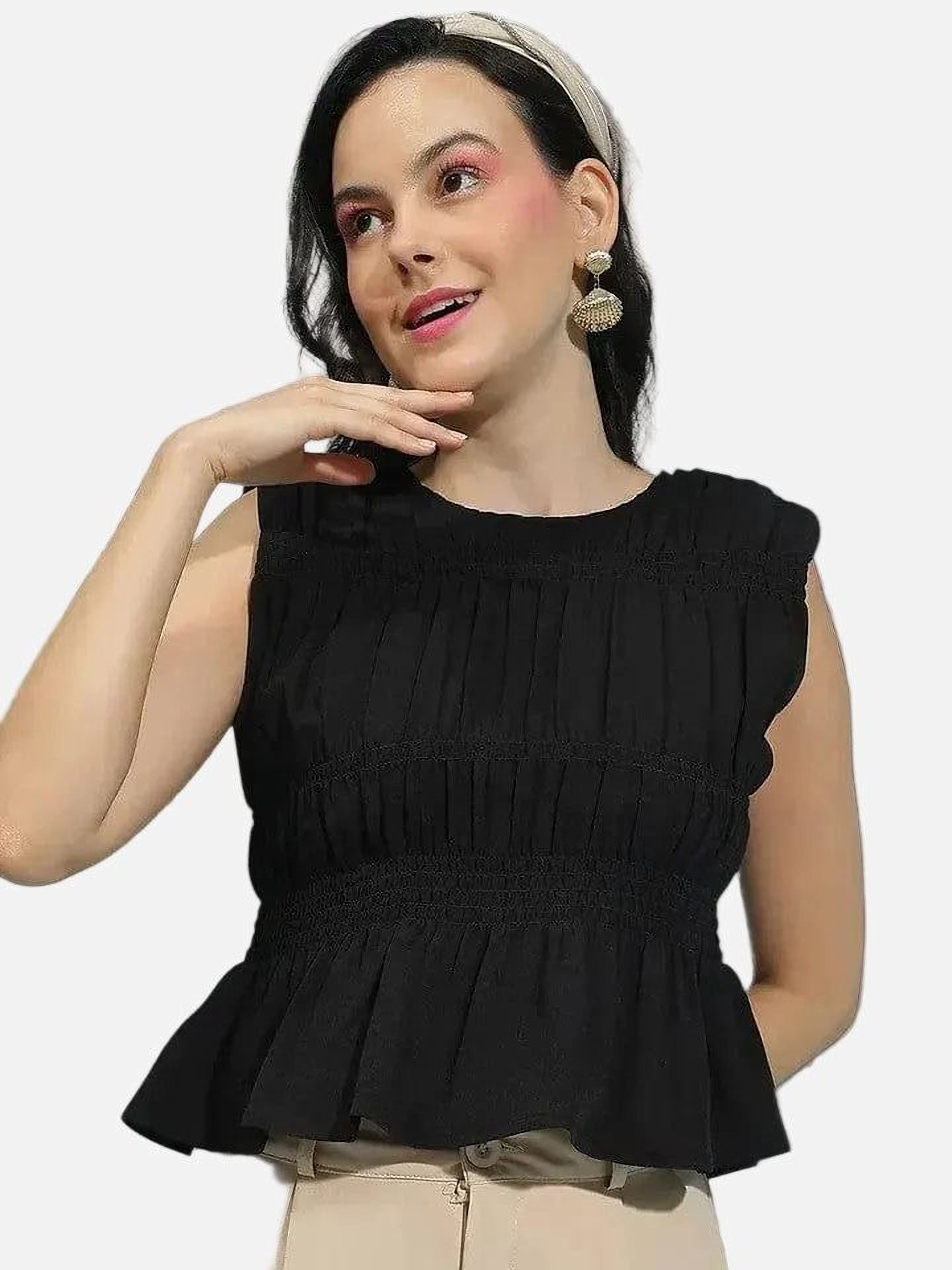 A woman with dark hair wearing a black sleeveless top and a headband is smiling and looking to the side.