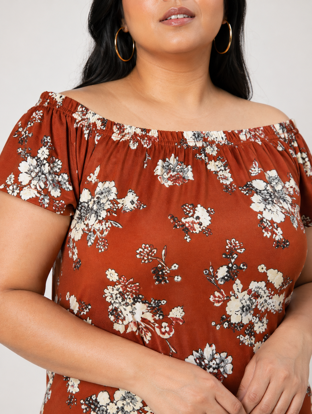 Plus size woman in off-shoulder floral dress with rust brown base and short sleeves