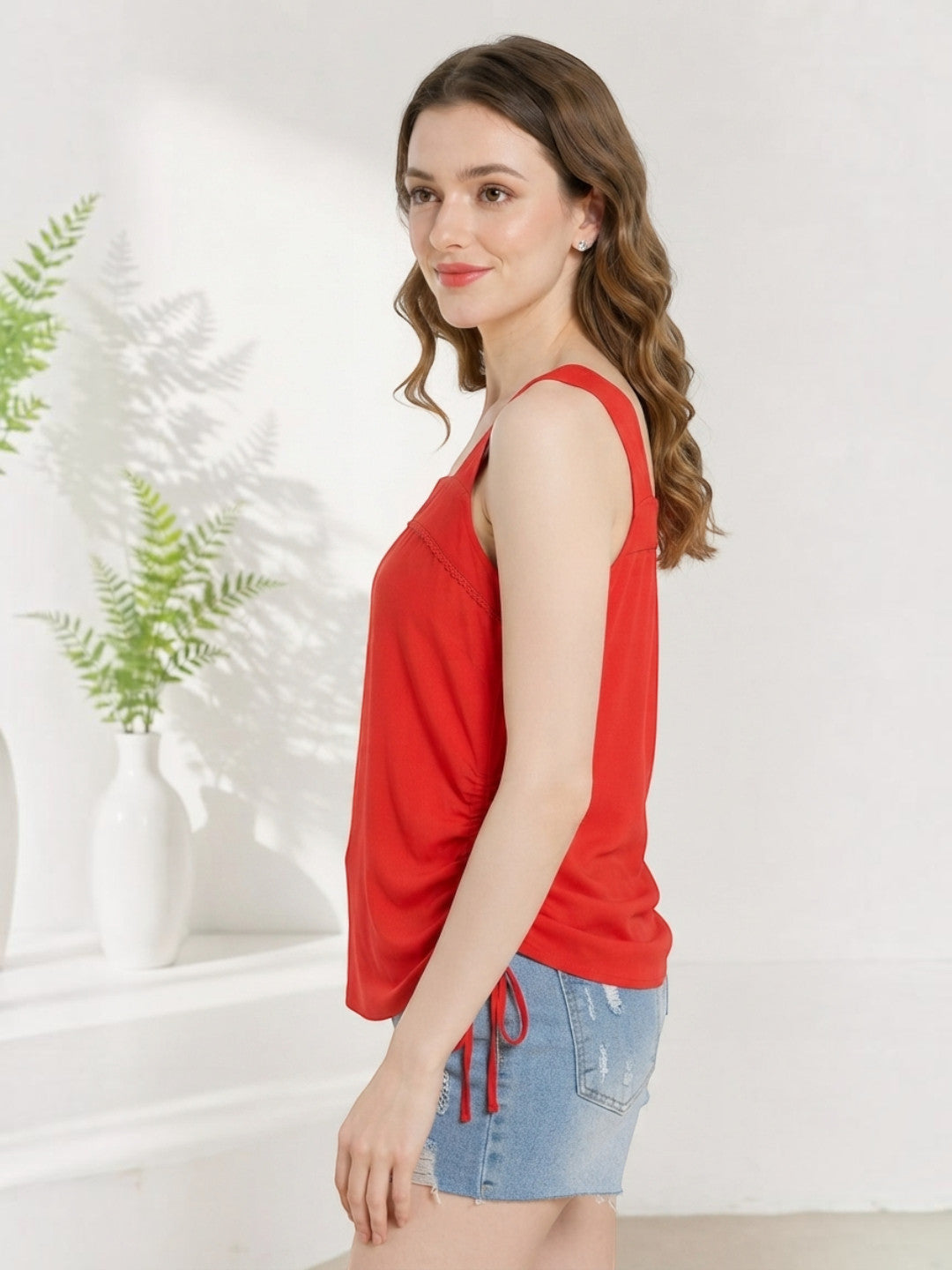 Red sleeveless top with side tie detail, paired with distressed denim shorts for casual summer wear