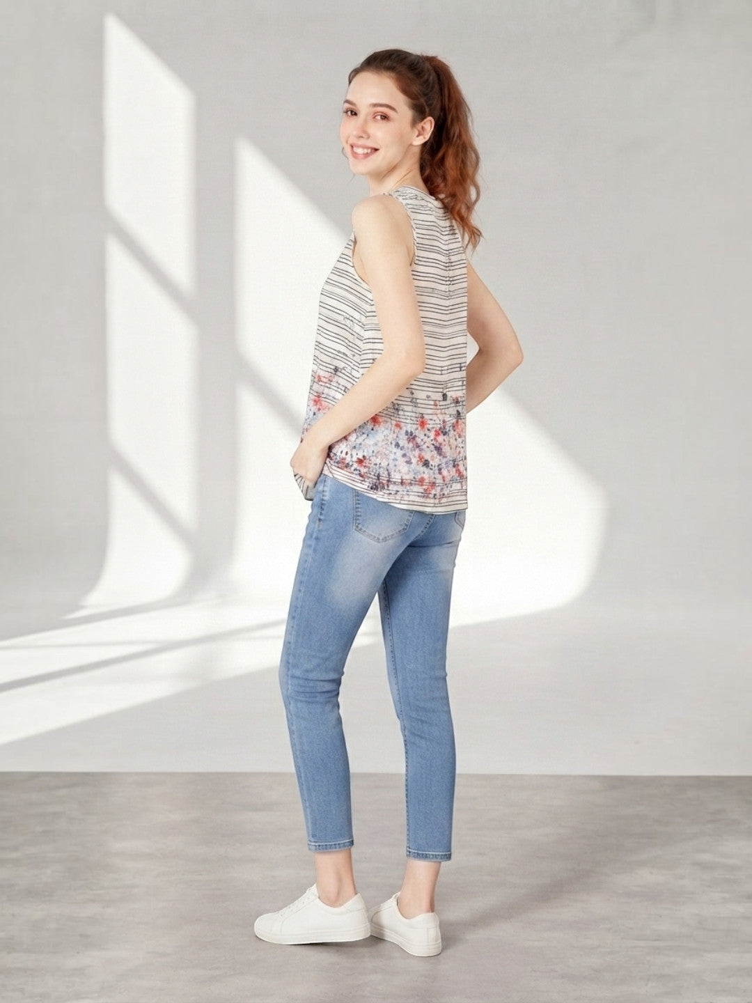 Woman in striped floral sleeveless top and blue jeans, casual summer outfit