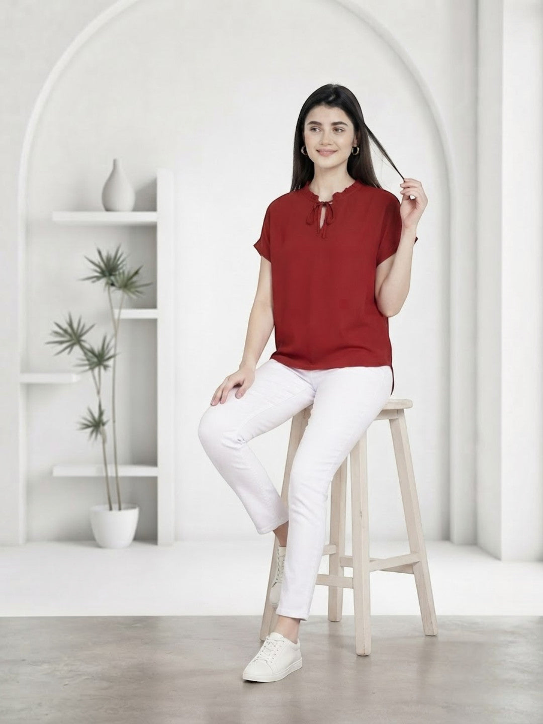 Woman in red tie-neck top and white pants, stylish plus size fashion outfit