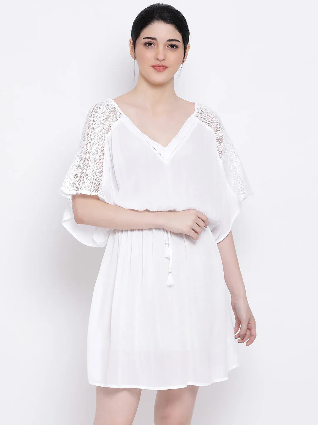 A woman wearing a white dress with lace sleeves and a v-neck, posing against a white background.