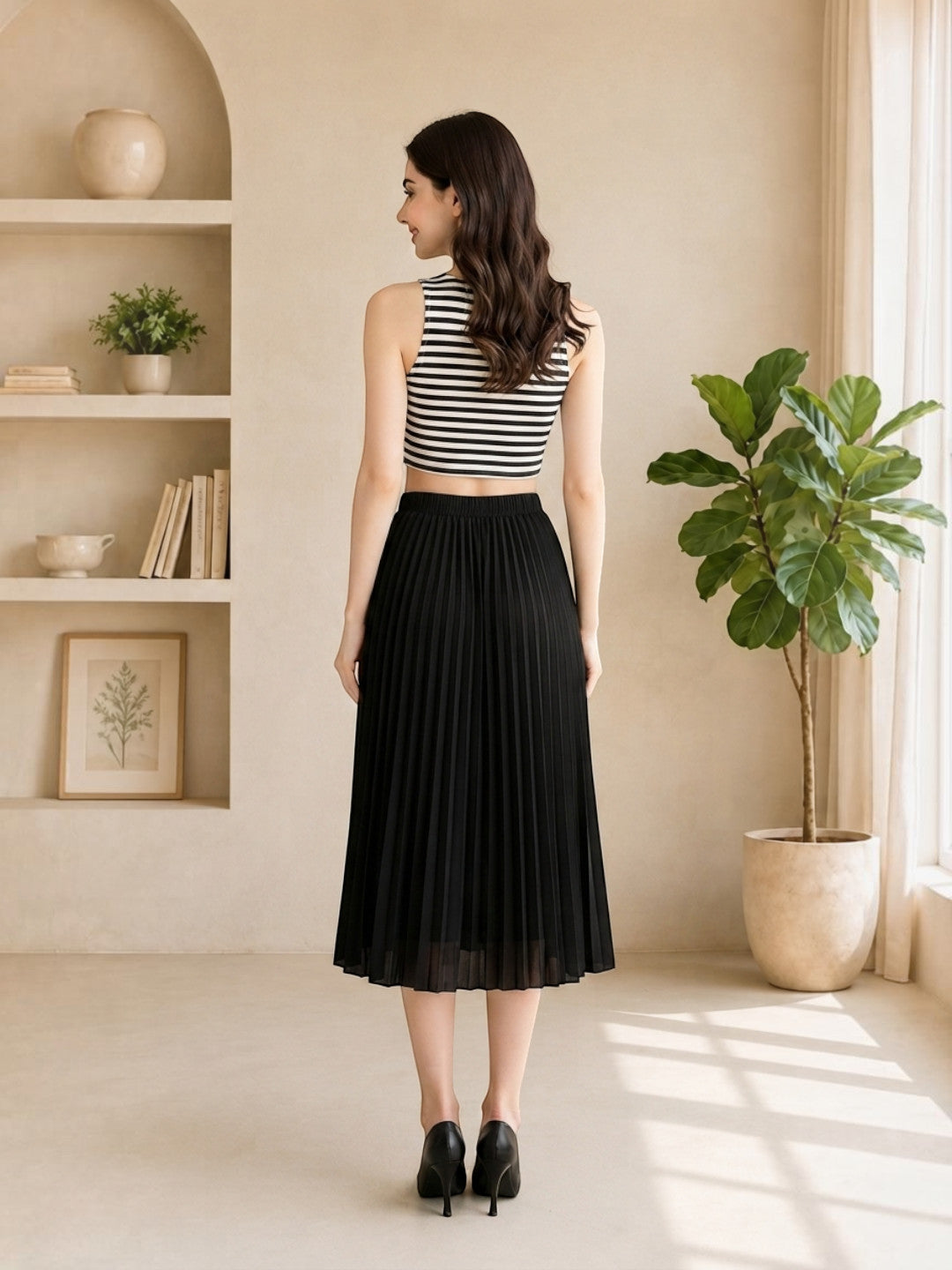 Woman in black pleated midi skirt with striped crop top, stylish plus size fashion outfit