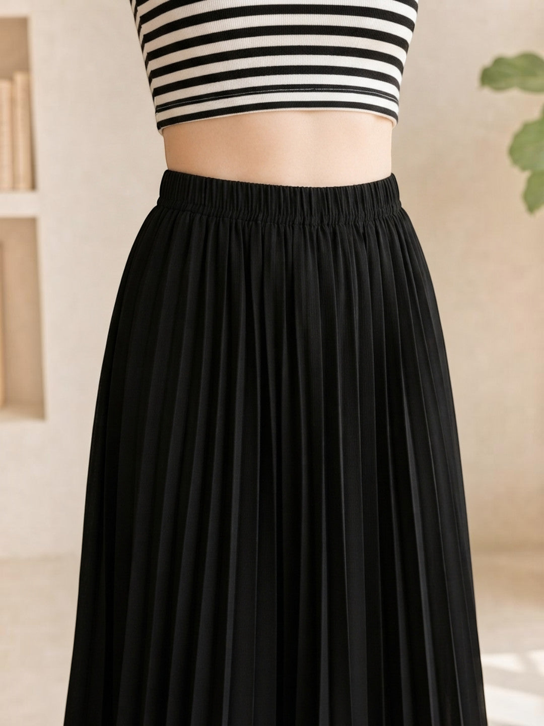 Black pleated midi skirt with elastic waist, paired with striped crop top for women's fashion