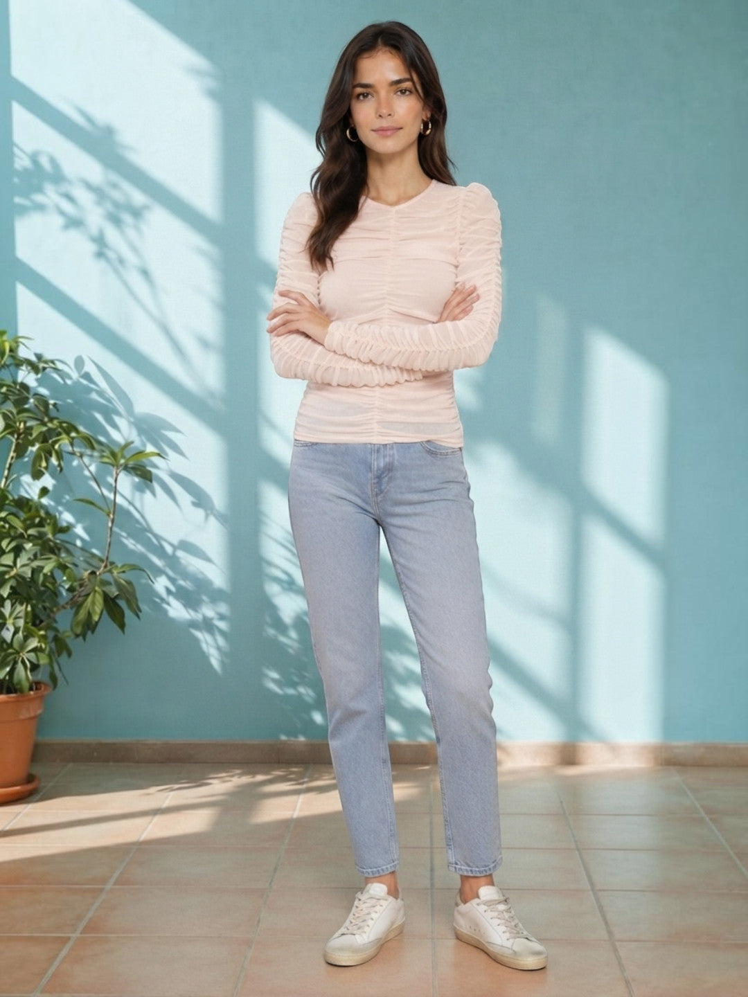 Woman in blush ruched long sleeve top and light wash jeans, stylish casual outfit for women
