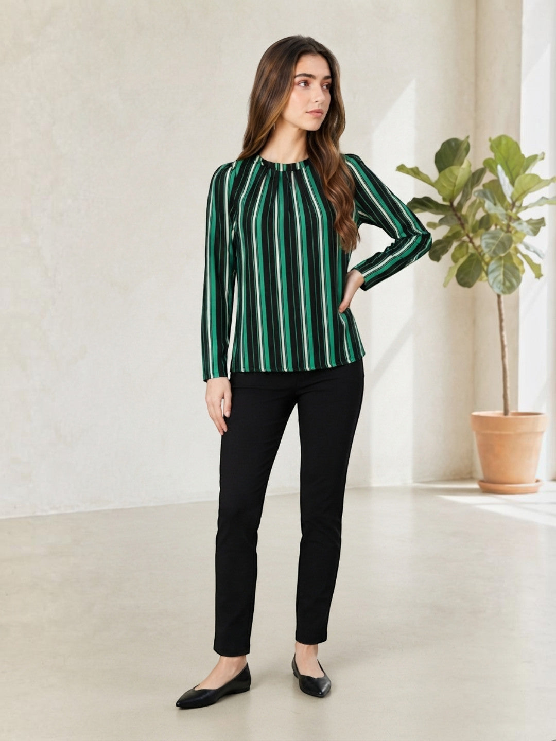 Woman wearing green and black striped long sleeve blouse with black pants, stylish office outfit