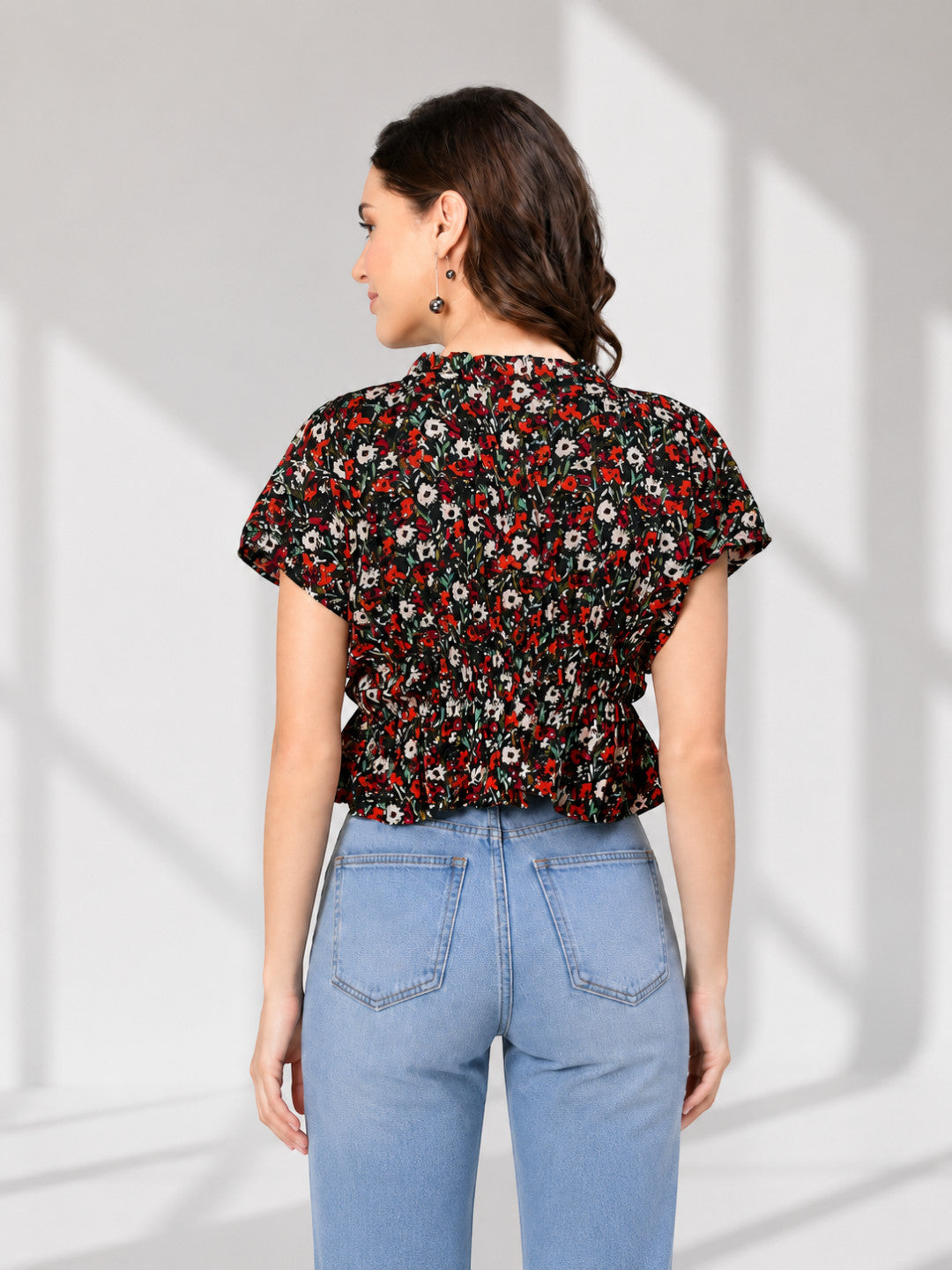 Floral print peplum top with short sleeves, paired with light blue jeans, back view