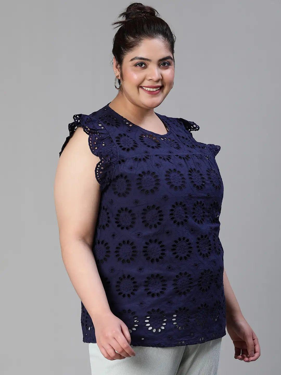 A woman wearing a navy blue top with a floral pattern and a bun hairstyle, smiling at the camera.