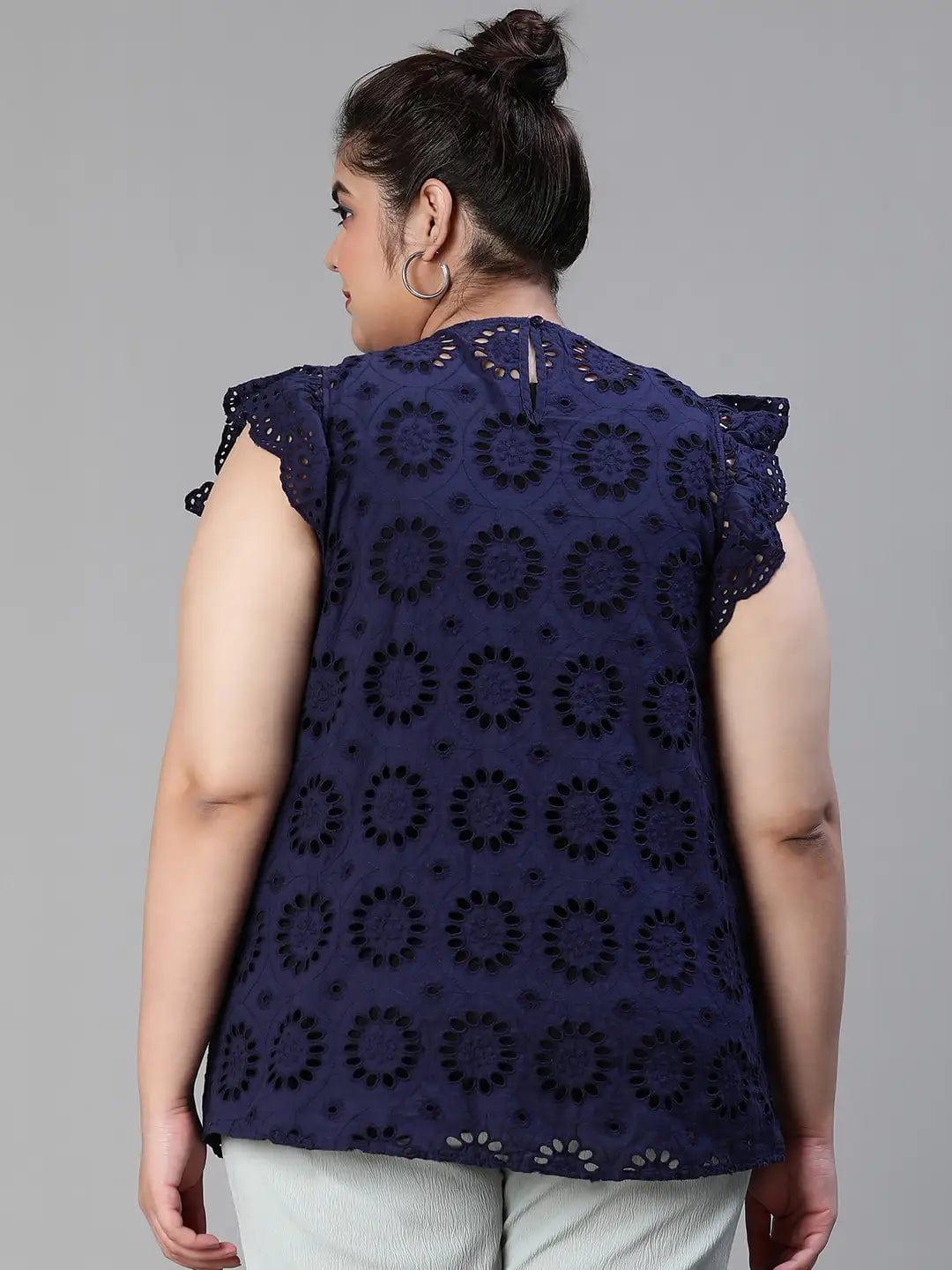 A woman wearing a navy blue top with a floral pattern and a bun hairstyle, smiling at the camera.