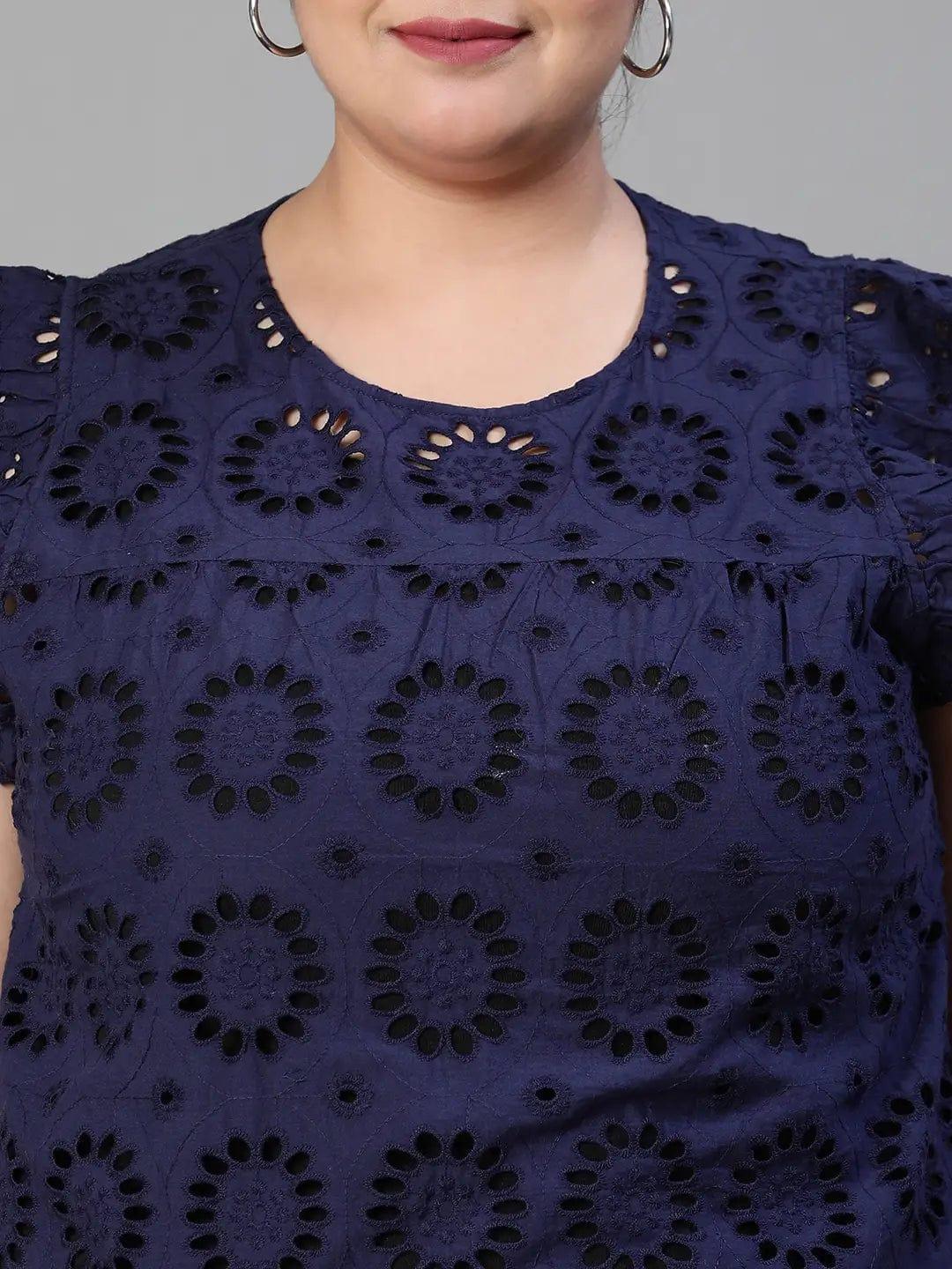 A woman wearing a navy blue top with a floral pattern and a bun hairstyle, smiling at the camera.