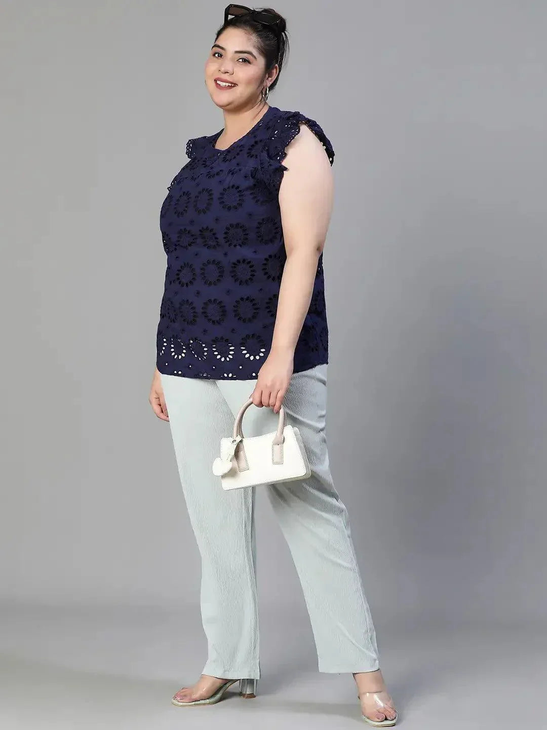 A woman wearing a navy blue top with a floral pattern and a bun hairstyle, smiling at the camera.
