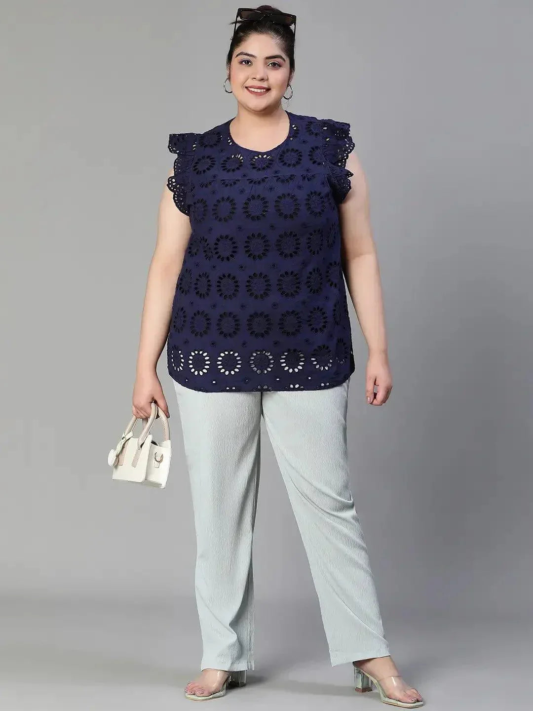 A woman wearing a navy blue top with a floral pattern and a bun hairstyle, smiling at the camera.