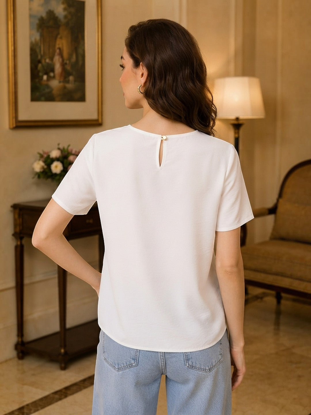 White women's blouse with back keyhole detail paired with light blue jeans