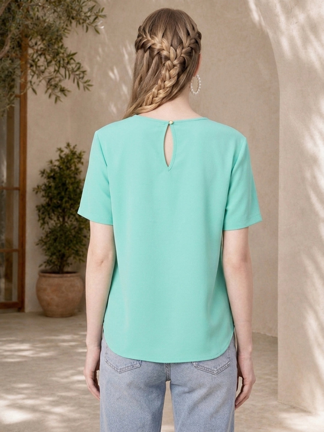 Mint green women's blouse with back keyhole detail, paired with light denim jeans, ideal for casual fashion.