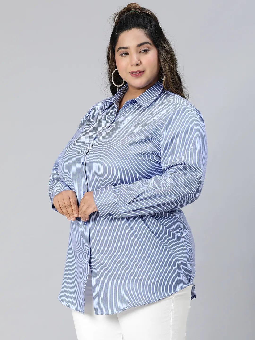 A woman with long brown hair wearing a blue striped button-up shirt and white pants, smiling at the camera.