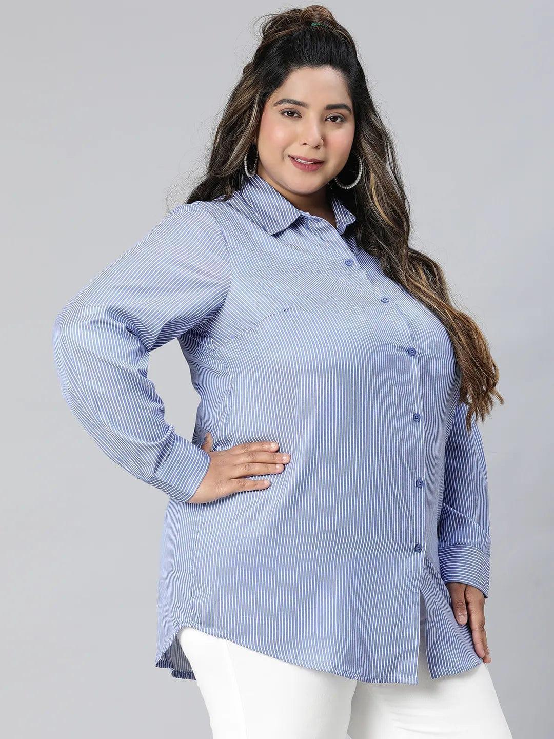 A woman with long brown hair wearing a blue striped button-up shirt and white pants, smiling at the camera.